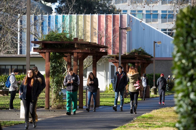 Students walk to class with Kadema Hall in the background.